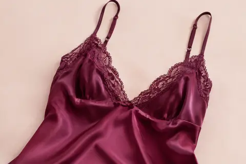 Nuisette en satin violet rouge avec décolleté en V bordé de dentelle et fines bretelles réglables.