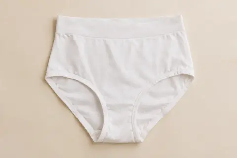 Culotte classique blanche taille haute en coton, présentée seule sur un fond crème doux
