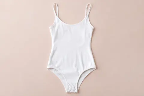 Body blanc Cotonella en coton bi-élastique, à fines bretelles et entrejambe ouvrant.
