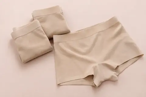 Trois shortys beige pour femme, coupe boxer mi-cuisse et finition sans couture, disposés sur un fond crème.