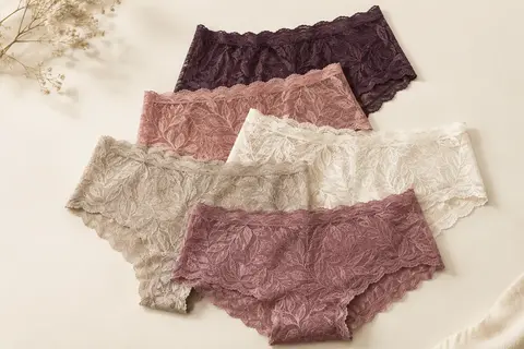 Lot de cinq culottes boxer en dentelle à motif feuillage et bords ondulés sur fond crème.