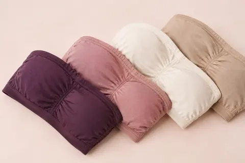 Quatre soutiens-gorge bandeau unis sans bretelles disposés sur un fond crème doux