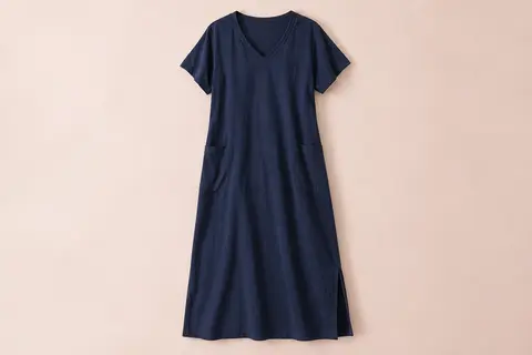 Chemise de nuit longue bleu foncé à manches courtes, col V, poches latérales et fente sur fond crème.