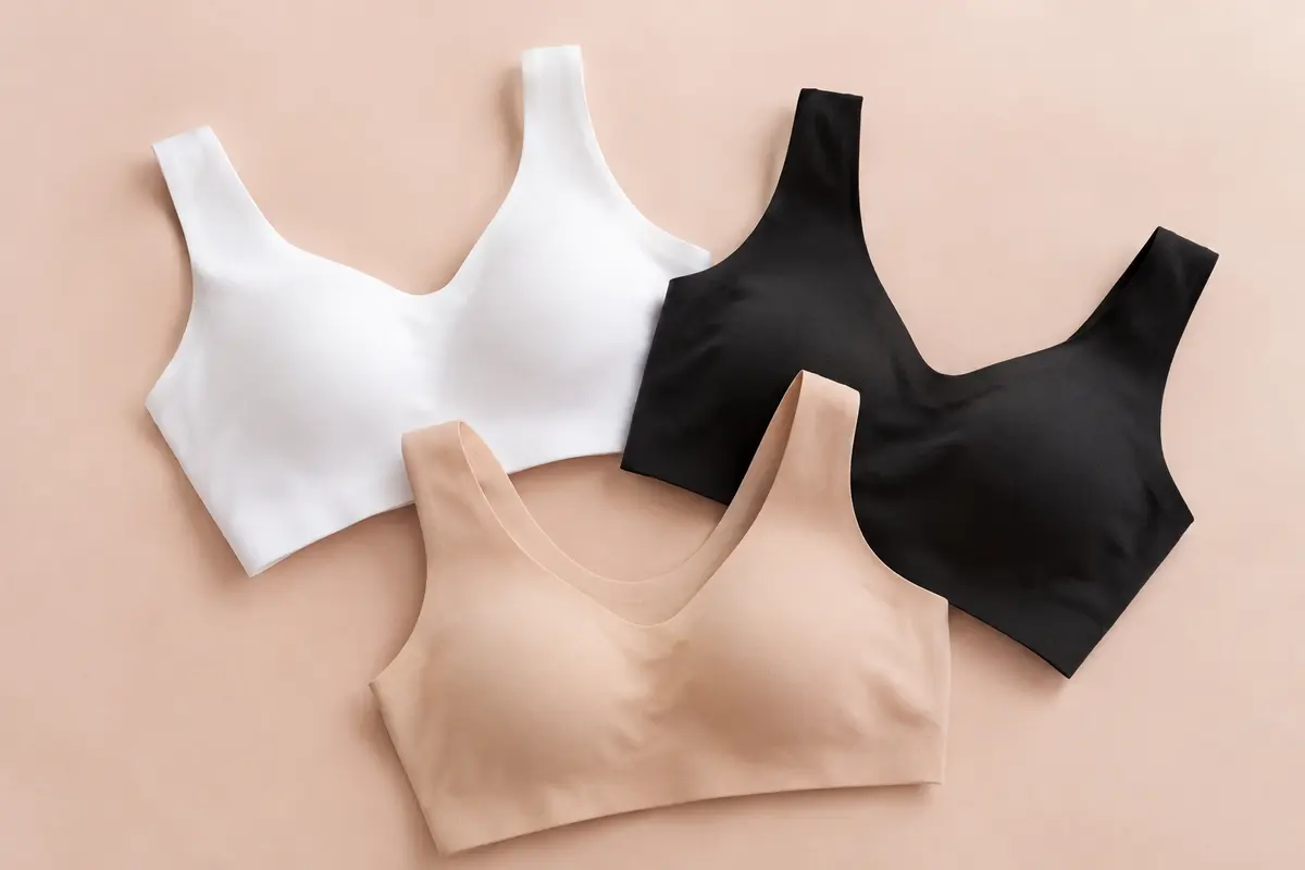 Lot de trois soutiens-gorge sans armatures en microfibre, en blanc, noir et naturel, posé sur un fond doux.