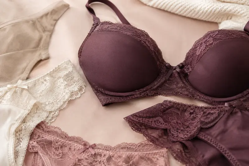 Détails de lingerie en maille et dentelle, présentés dans une lumière douce sur fond poudré.